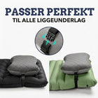 Campingpuden fastgjort med rem og spænde på et sort og et grønt liggeunderlag, nærbillede af spændet