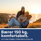 Tre venner ler sammen i campingstolen på en klippe ved havet i solnedgangen, med teksten Støtter 150 kg