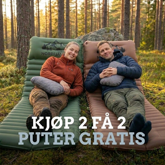 Par hviler på grønn og brun luftmadrass PRO V2 med grå puter i furuskog, med tilbudstekst om gratis puter