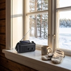 Beredskapsradio med solcelle vendt oppover på en vinduskarm i en hytte, snødekt skog og innsjø utenfor