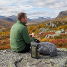 Vandrer holder pause på bjerget med håndkrank-radioen og rygsækken på en sten i efterårsfarver