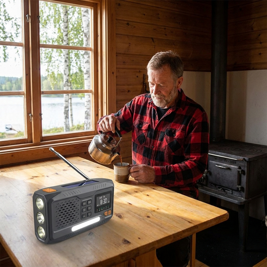 Mies kaataa kahvia mökillä olevassa keittiössä DAB+ -radion kanssa pöydällä ja järvi näkyvissä ikkunan ulkopuolella
